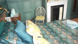 A bedroom with a bed, a chair, a fireplace, and a mirror on the wall. - The George B&B (Weymouth)