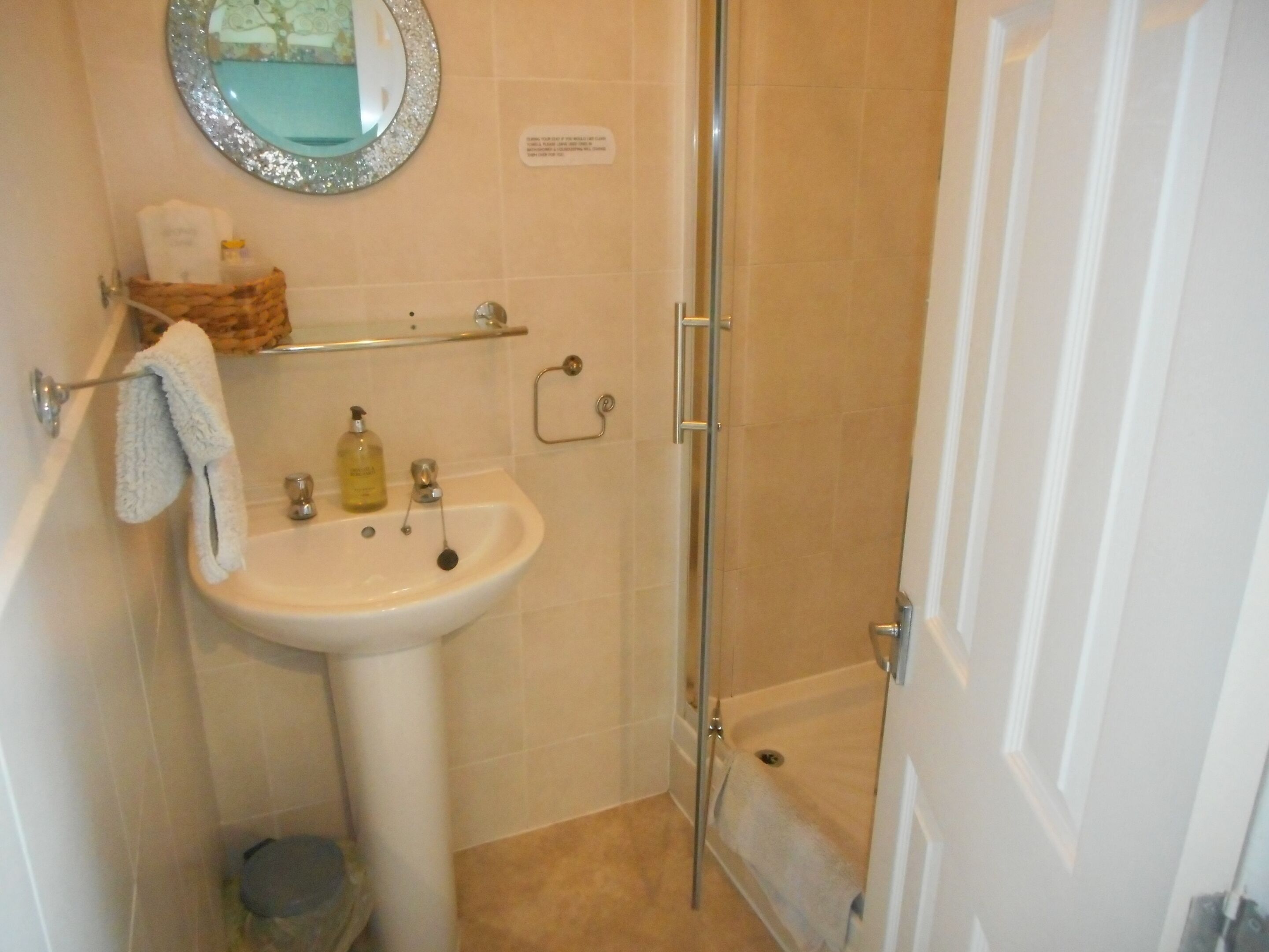 A bathroom with a sink, mirror, and shower.