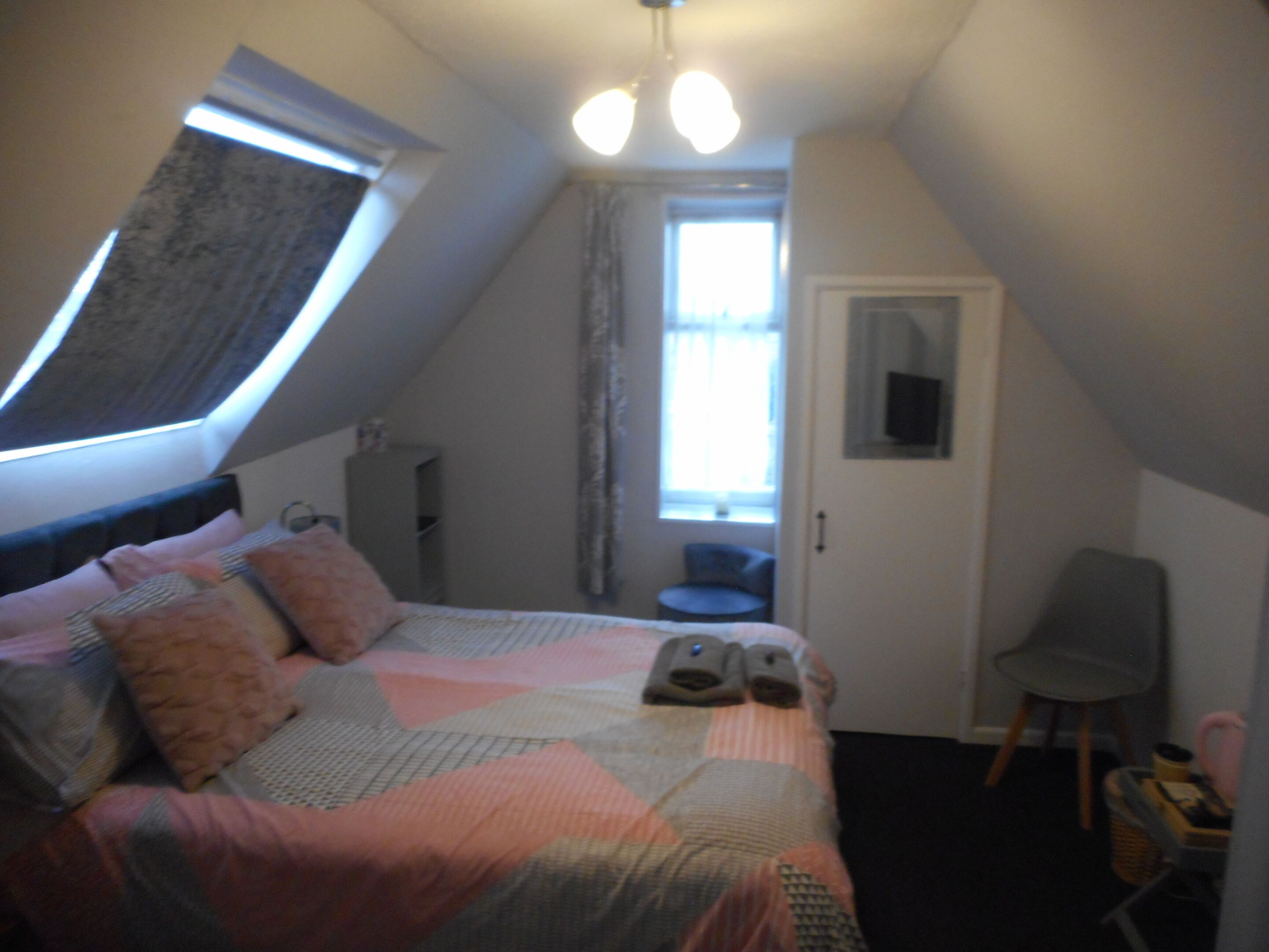 A small, cozy room with a bed, a desk, a chair, and a window.