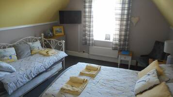 Une chambre avec deux lits, un téléviseur à écran plat, un radiateur et une fenêtre avec des rideaux.