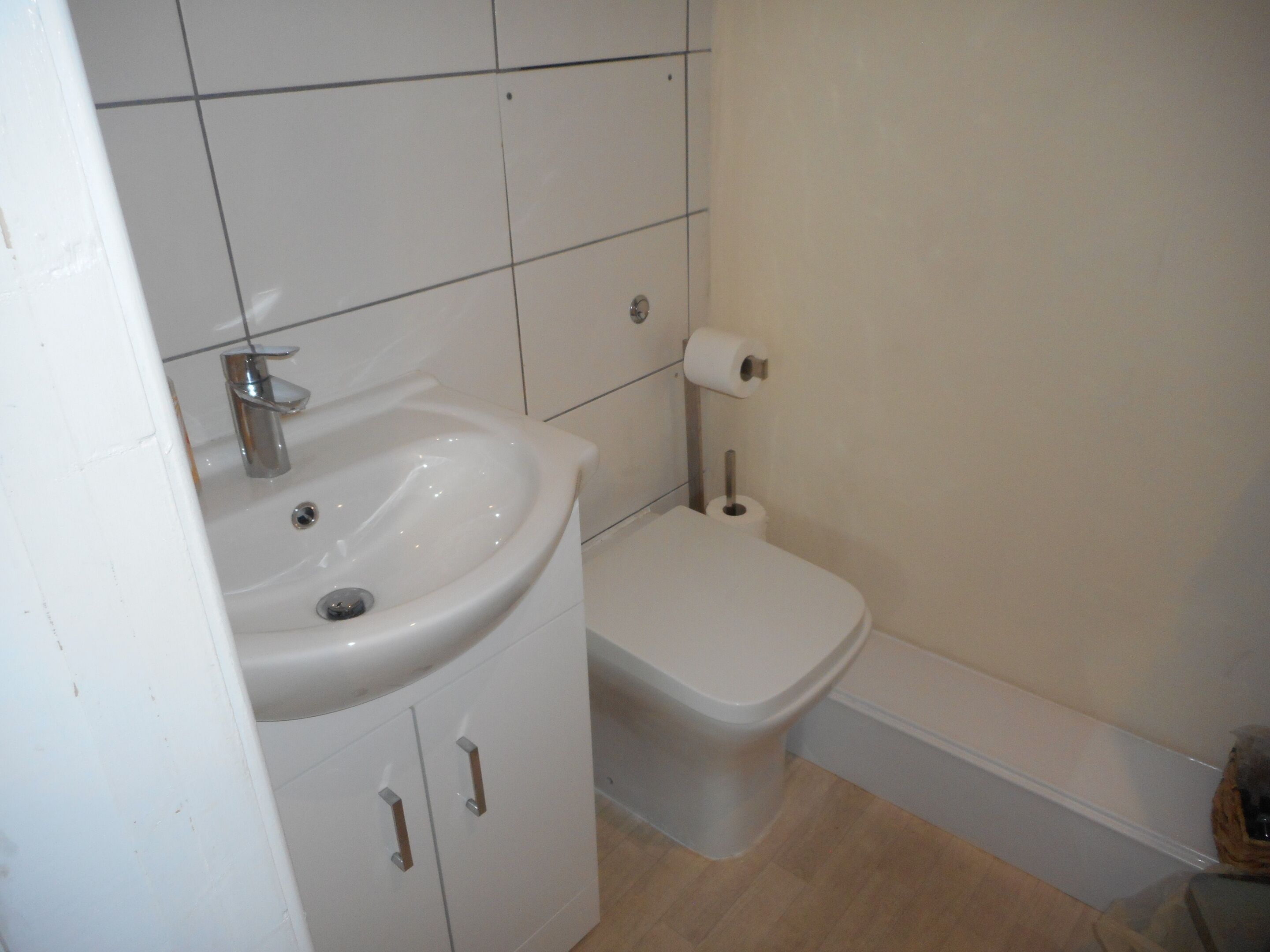 A bathroom with a sink, toilet, and a roll of toilet paper on the wall.