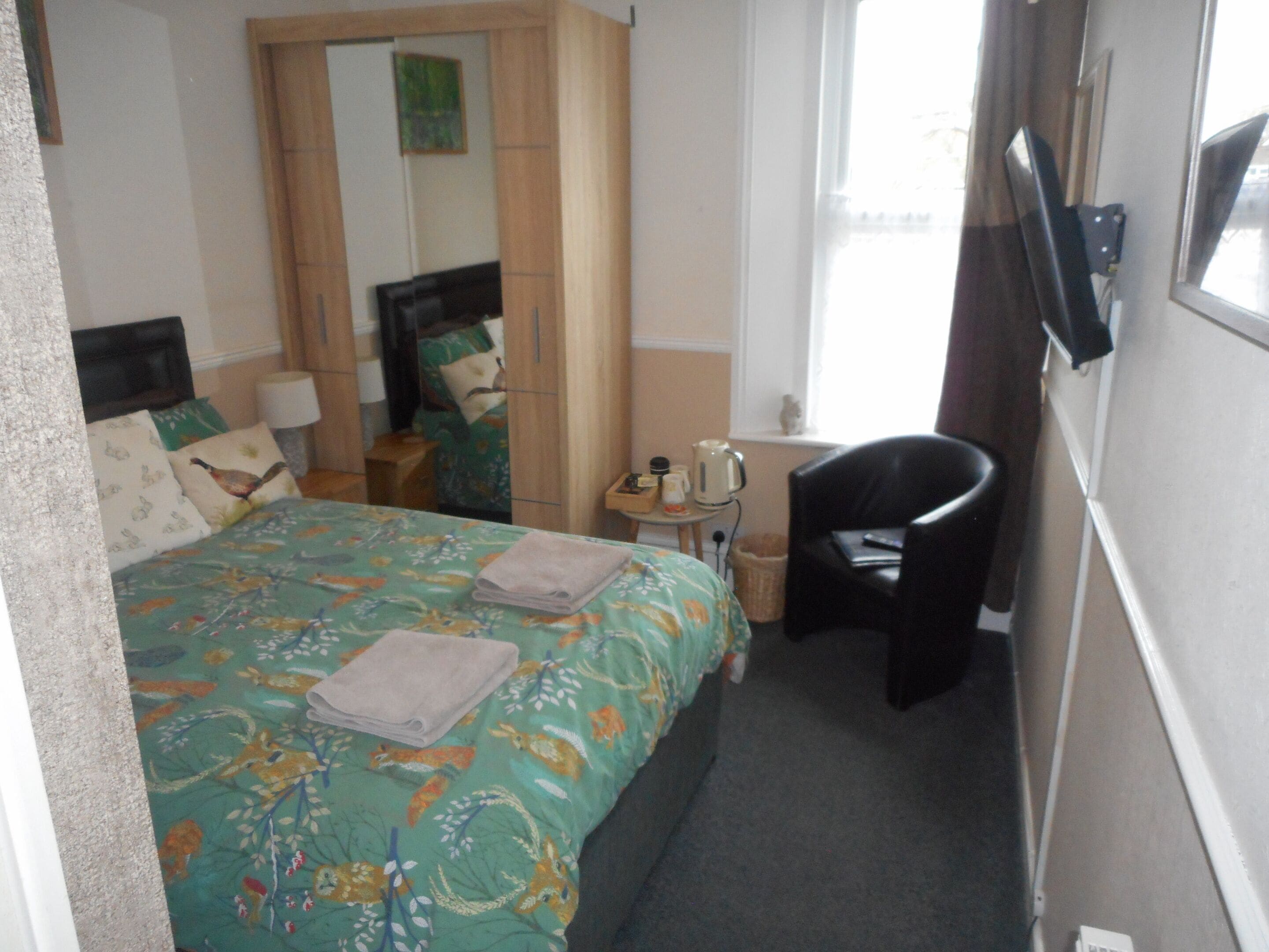 Een hotelkamer met een bed, een stoel, een kleine tafel en een raam.