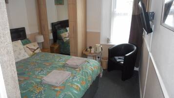 Een hotelkamer met een bed, een stoel, een kleine tafel en een raam.