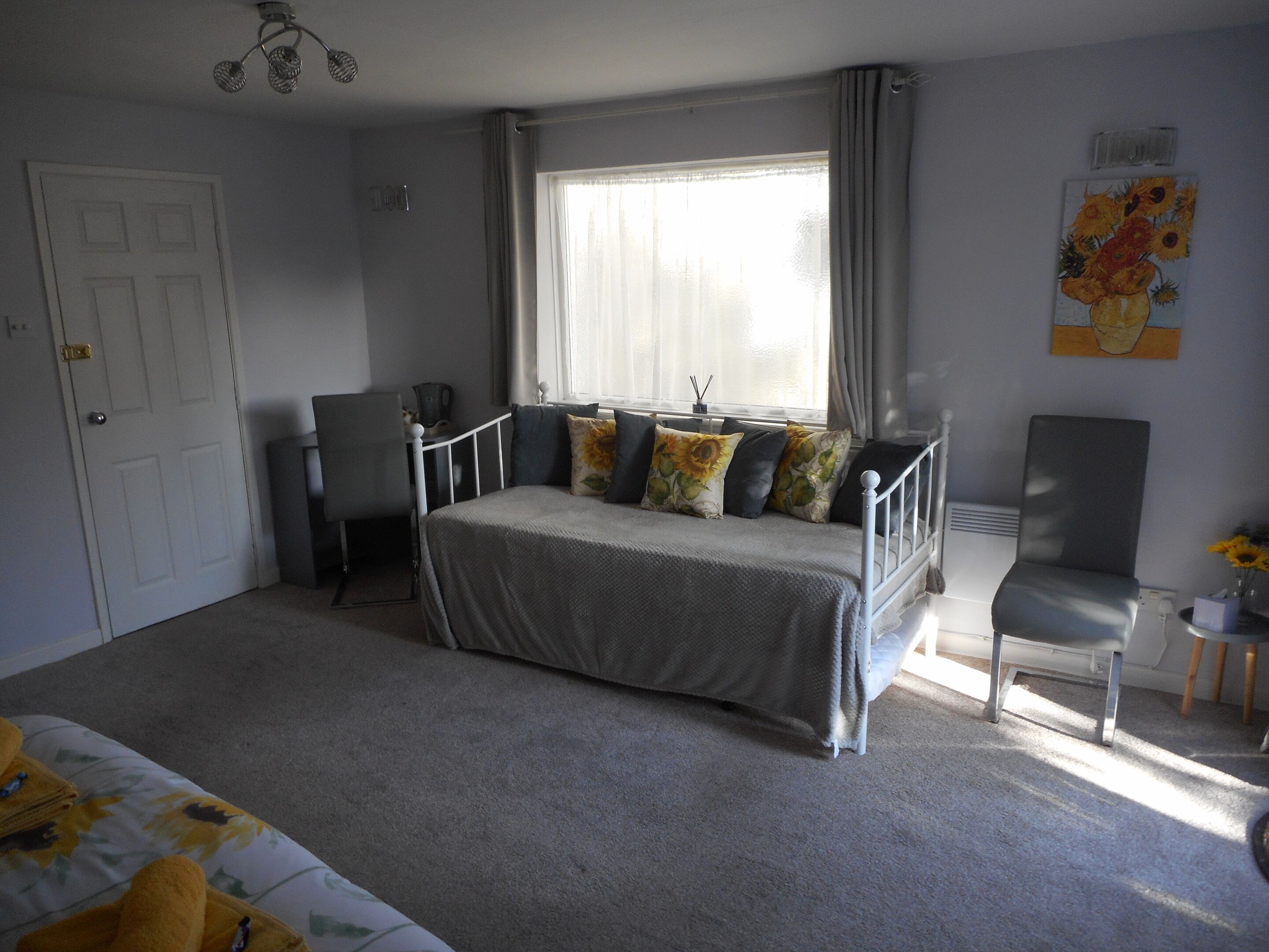 A bedroom with a bed, a chair, a desk, and a window with curtains.