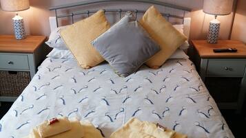 A neatly made bed with a patterned duvet, pillows, and folded towels.