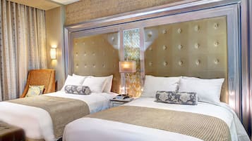 A hotel room with two beds, a headboard with a tufted design, a lamp, and a decorative mirror.