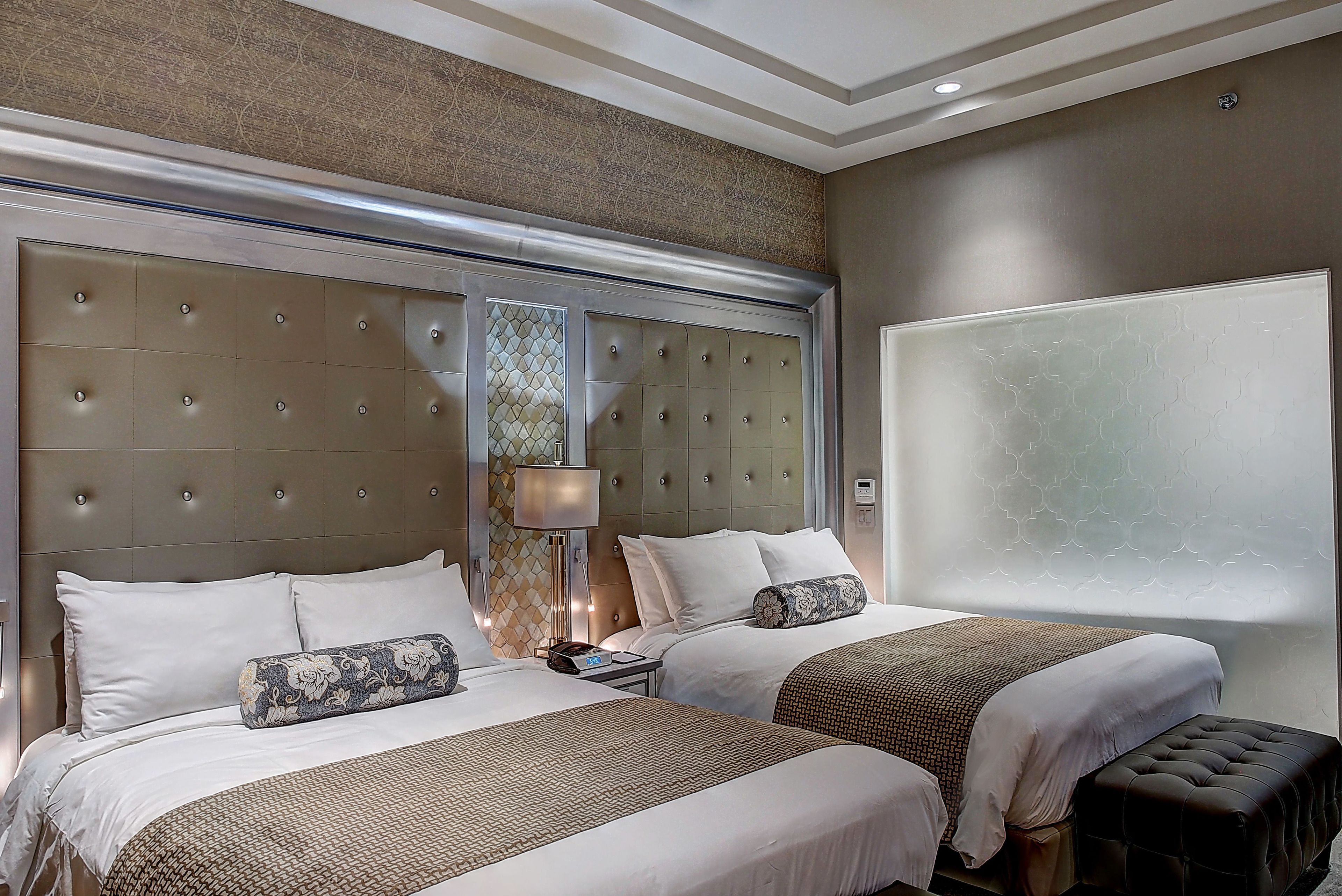 A hotel room with a large bed, two bedside tables, a lamp, and a window with a view.