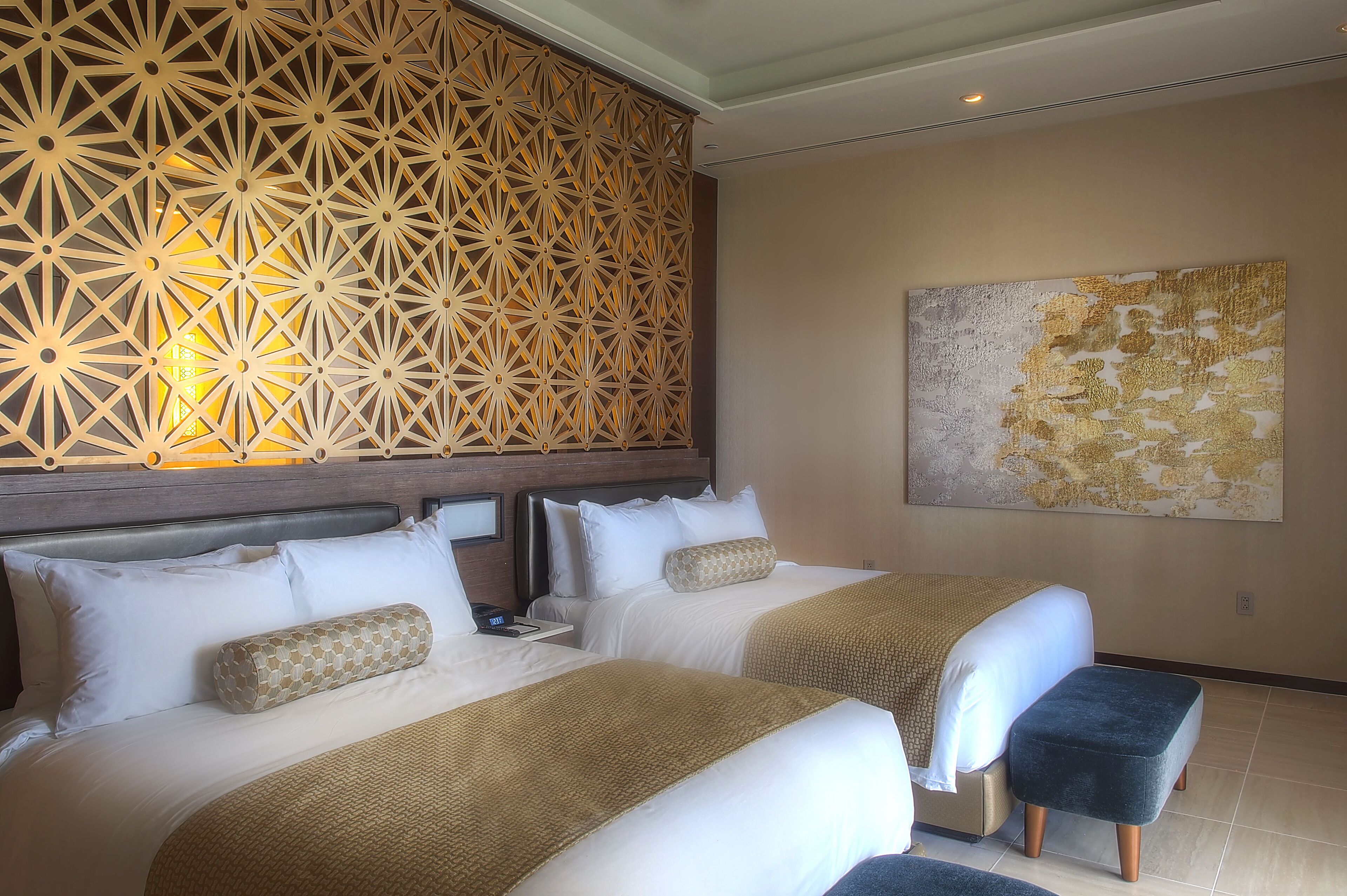 Habitación de hotel con dos camas, un adorno en la pared y un cuadro abstracto grande.