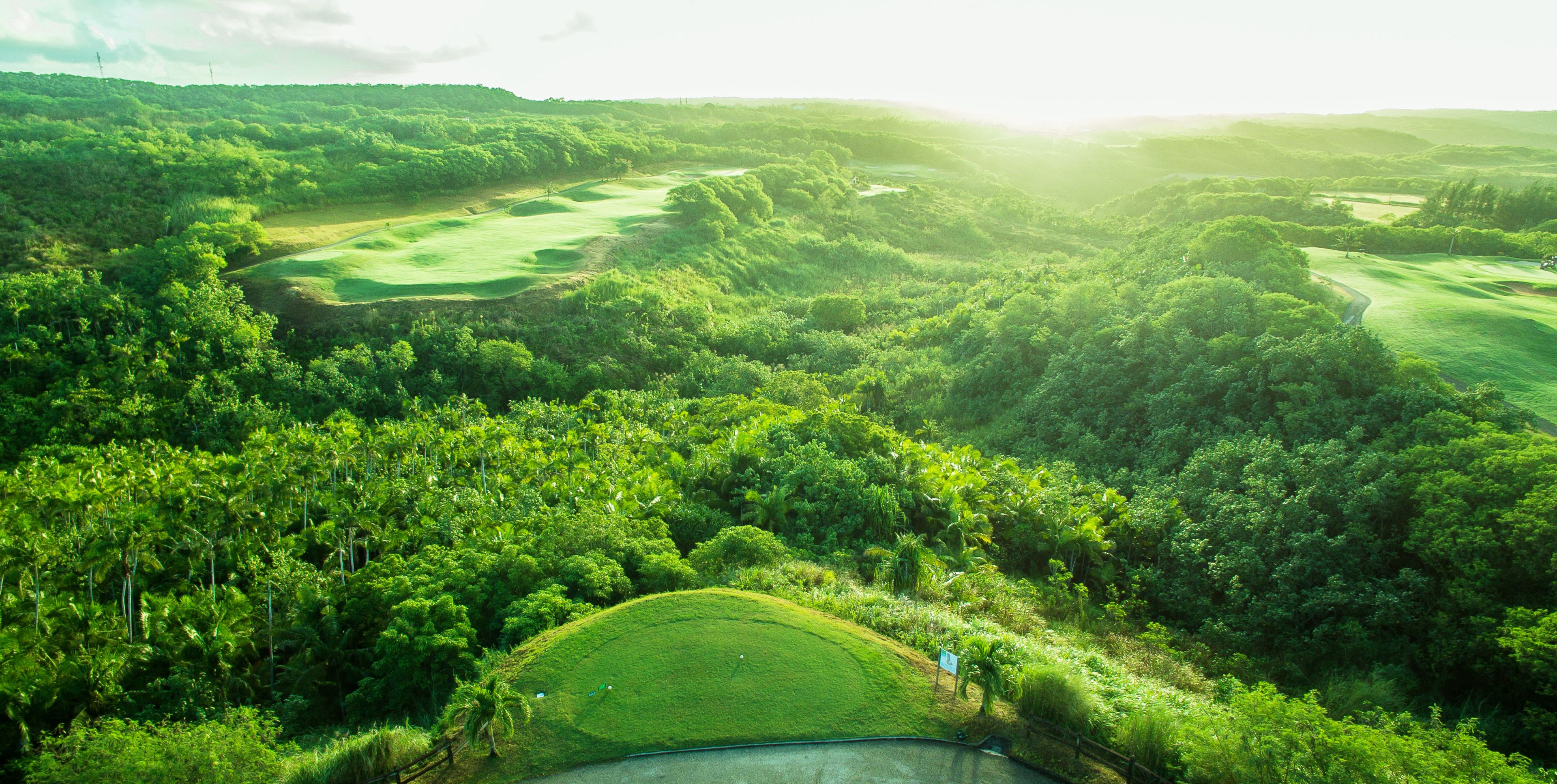 Un parcours de golf entouré d’une végétation luxuriante et de collines.