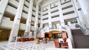 A spacious hotel lobby with multiple floors, a central staircase, and seating areas. - Leopalace Resort Guam (Yona)