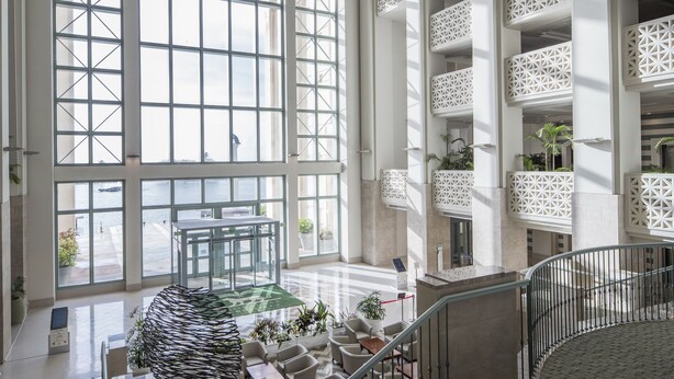 A spacious lobby with large windows, a central seating area, and a staircase. - Leopalace Resort Guam (Yona)