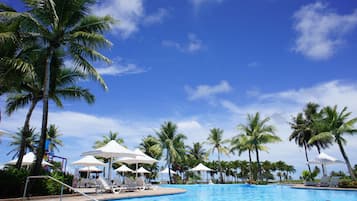 Una piscina al aire libre, sombrillas, sillones reclinables de piscina