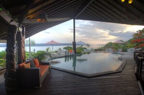 A covered outdoor area with a pool, seating, and a view of the water. - Deco Stop Lodge (Luganville)