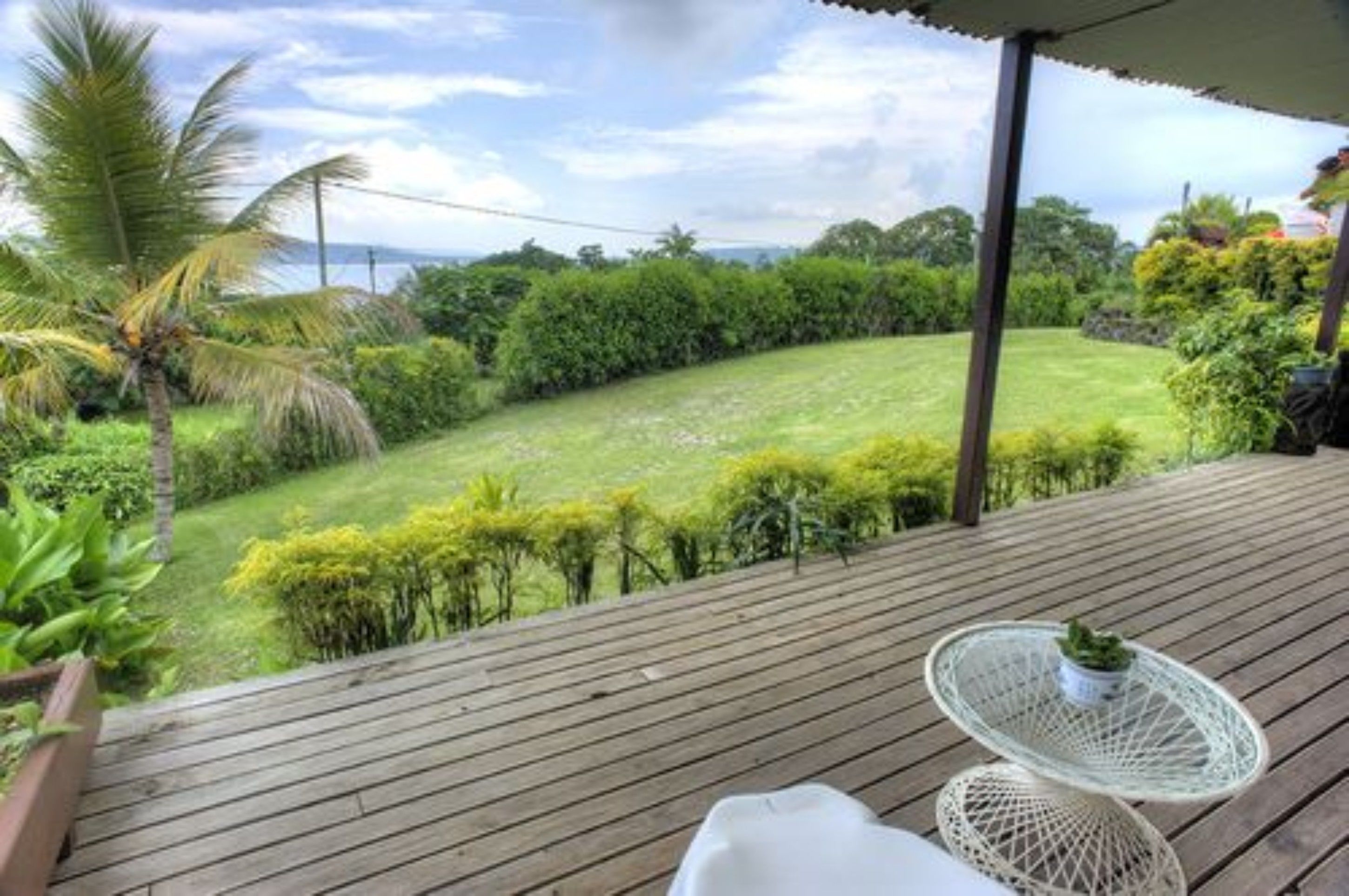 A wooden deck with a white round table and a small potted plant.