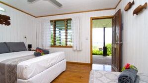 A hotel room with two beds, a ceiling fan, a window with blinds, and a door leading outside. - Deco Stop Lodge (Luganville)