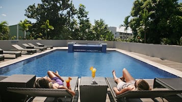 Un área junto a la piscina con sillones de descanso y una piscina.