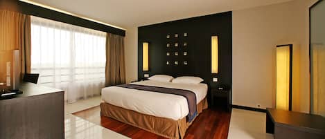 A modern hotel room with a large bed, a desk, and a seating area.