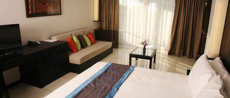 Una habitación de hotel con cama, escritorio, sofá y televisión.