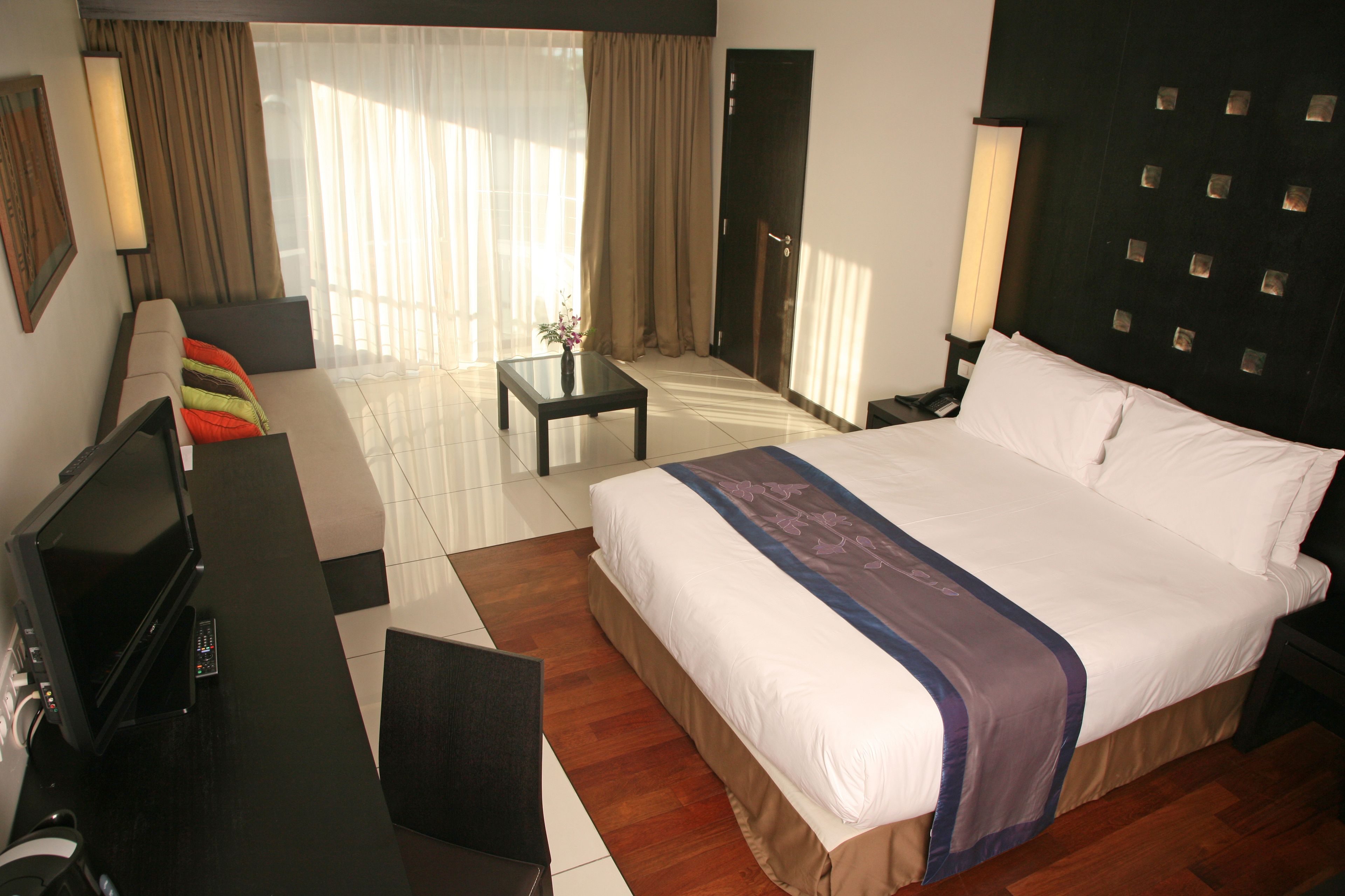 Una habitación de hotel con una cama grande, televisión, escritorio y una silla.