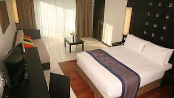 A hotel room with a large bed, a TV, a desk, and a chair.
