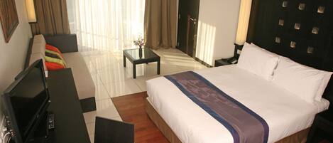 Una habitación de hotel con una cama grande, televisión, escritorio y una silla.