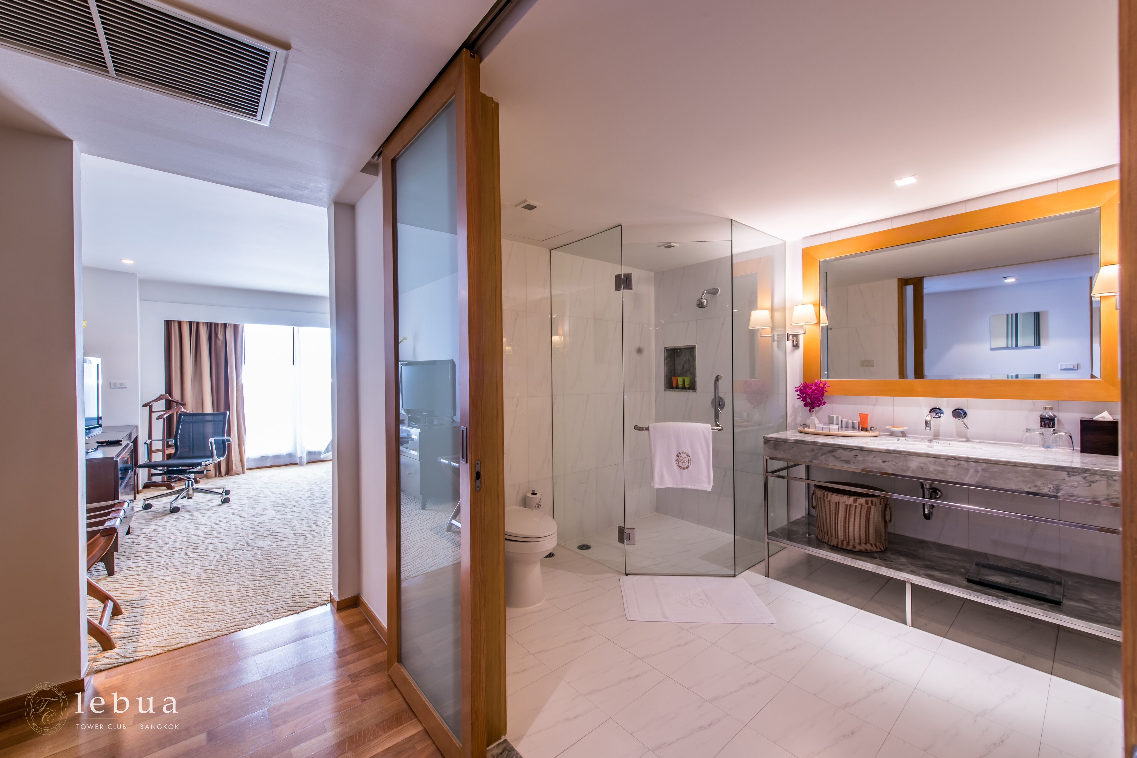 Une salle de bain moderne avec une douche à l’italienne en verre, un meuble-lavabo doté d’un grand miroir et des toilettes.