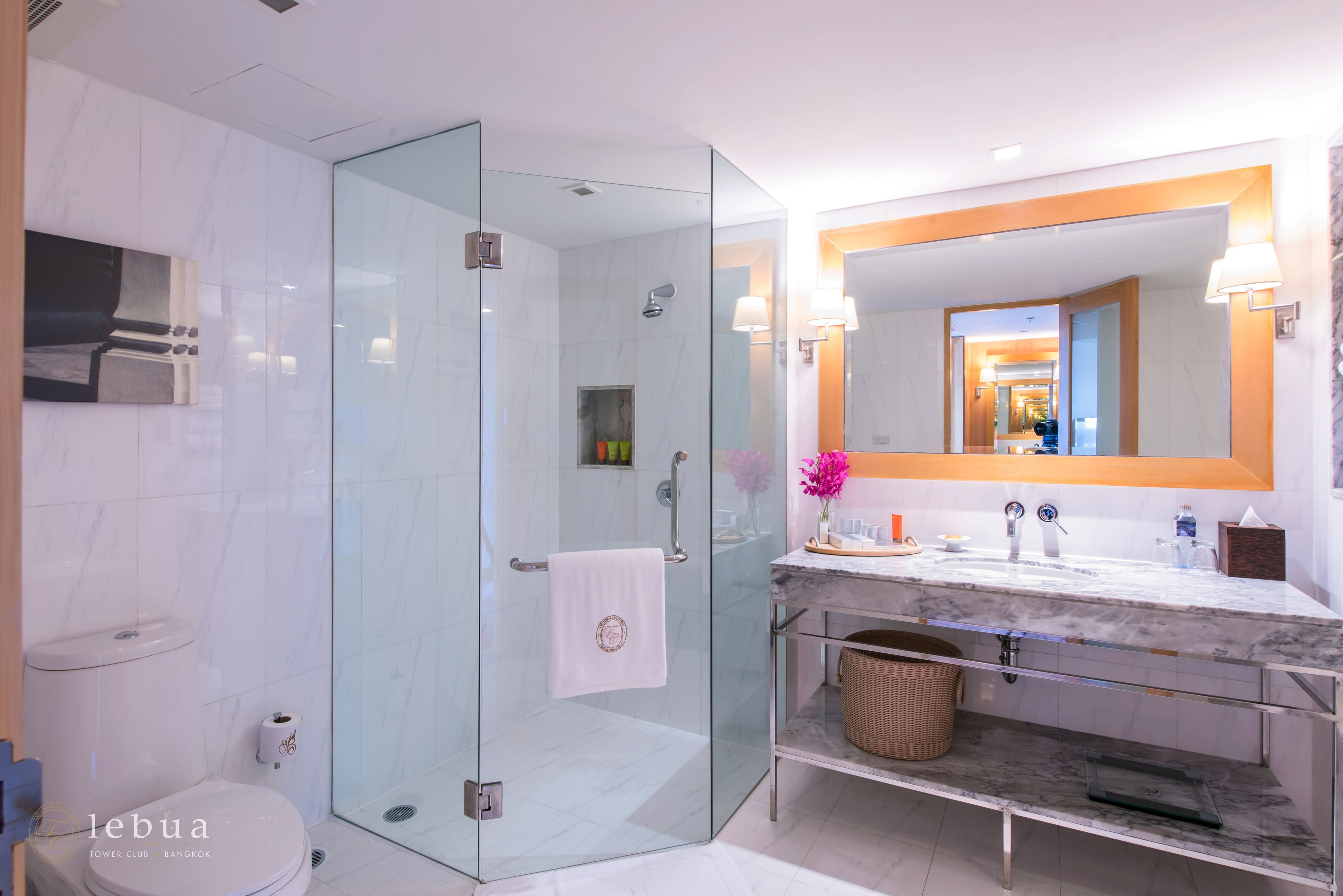 Une salle de bain moderne avec une douche à parois de verre, un lavabo en marbre et un grand miroir.