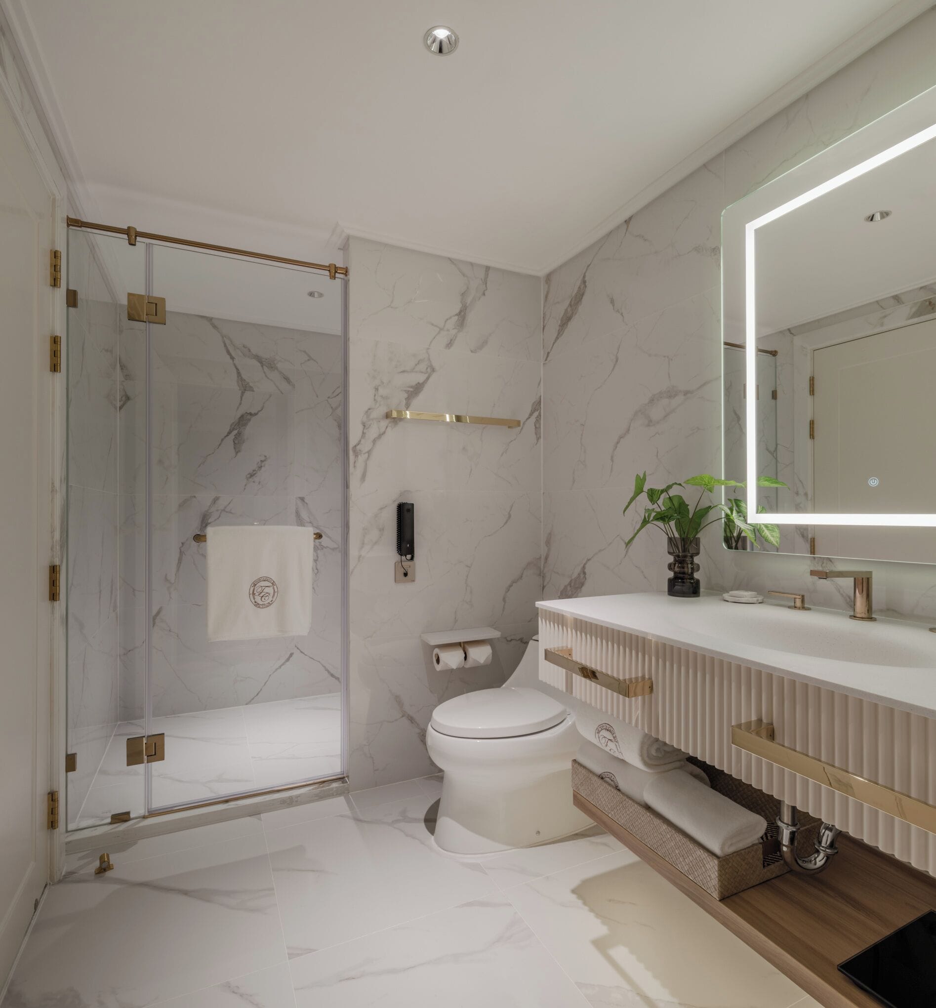 Un baño moderno con cabina de ducha de vidrio, inodoro y tocador con espejo.