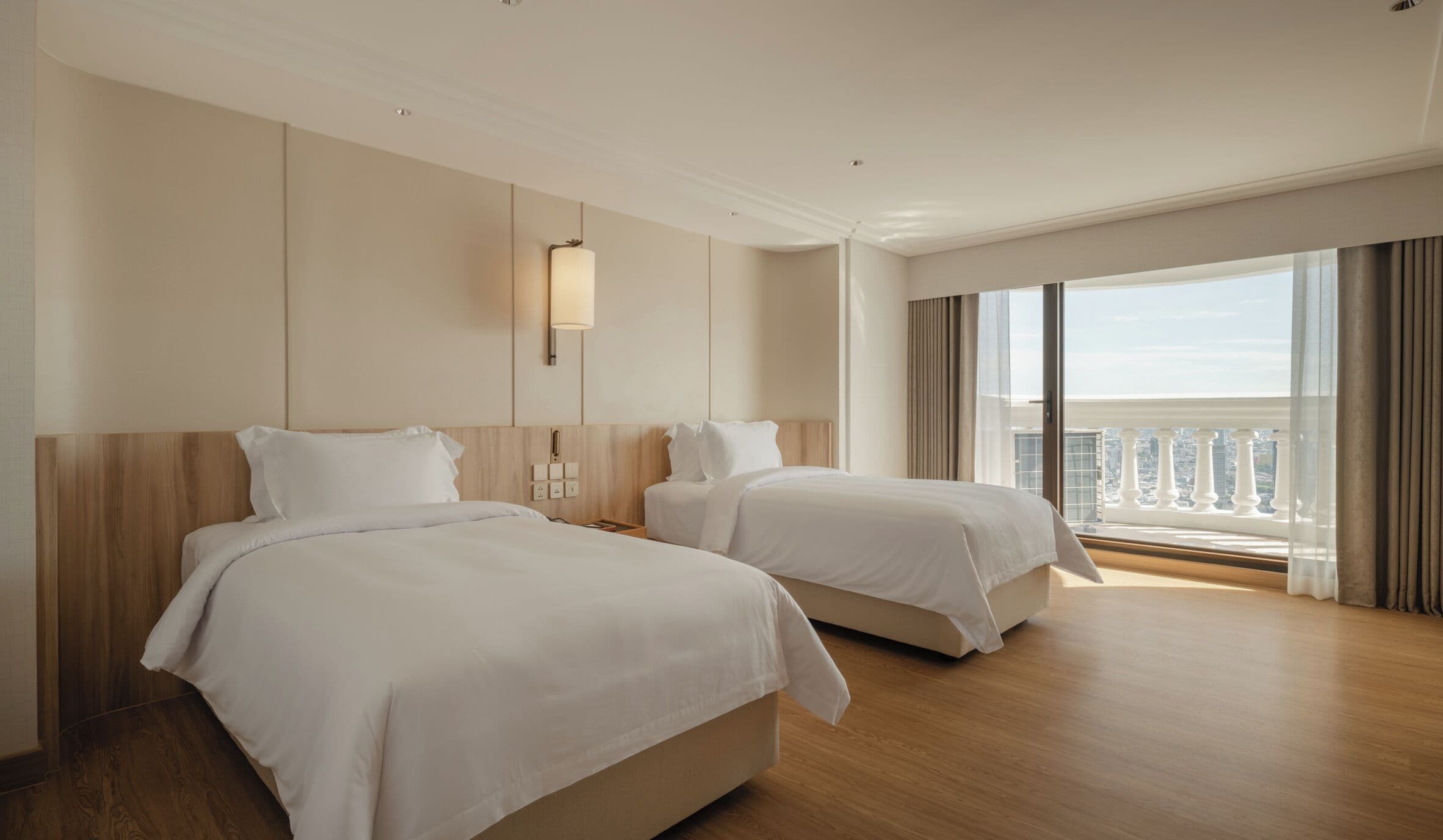 A hotel room with two beds, a large window with a city view, and a modern design.