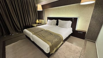 Camera d'albergo con un letto grande, due comodini, una testiera, una tenda e due lampade a parete.