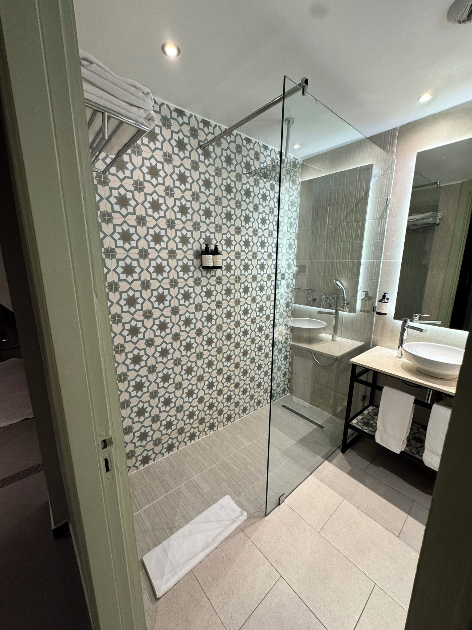 A modern bathroom with a glass shower enclosure, a sink, and a mirror.
