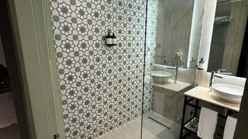 A modern bathroom with a glass shower enclosure, a sink, and a mirror.