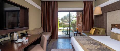 A hotel room with a bed, a desk, a television, a coffee maker, and a view of the outdoors.