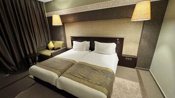 A hotel room with a large bed, two bedside tables, a chair, and a lamp.