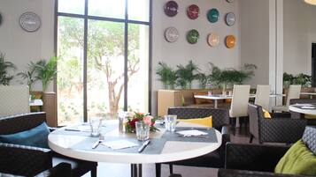 Un comedor con mesas redondas, sillas y una variedad de platos decorativos en la pared.