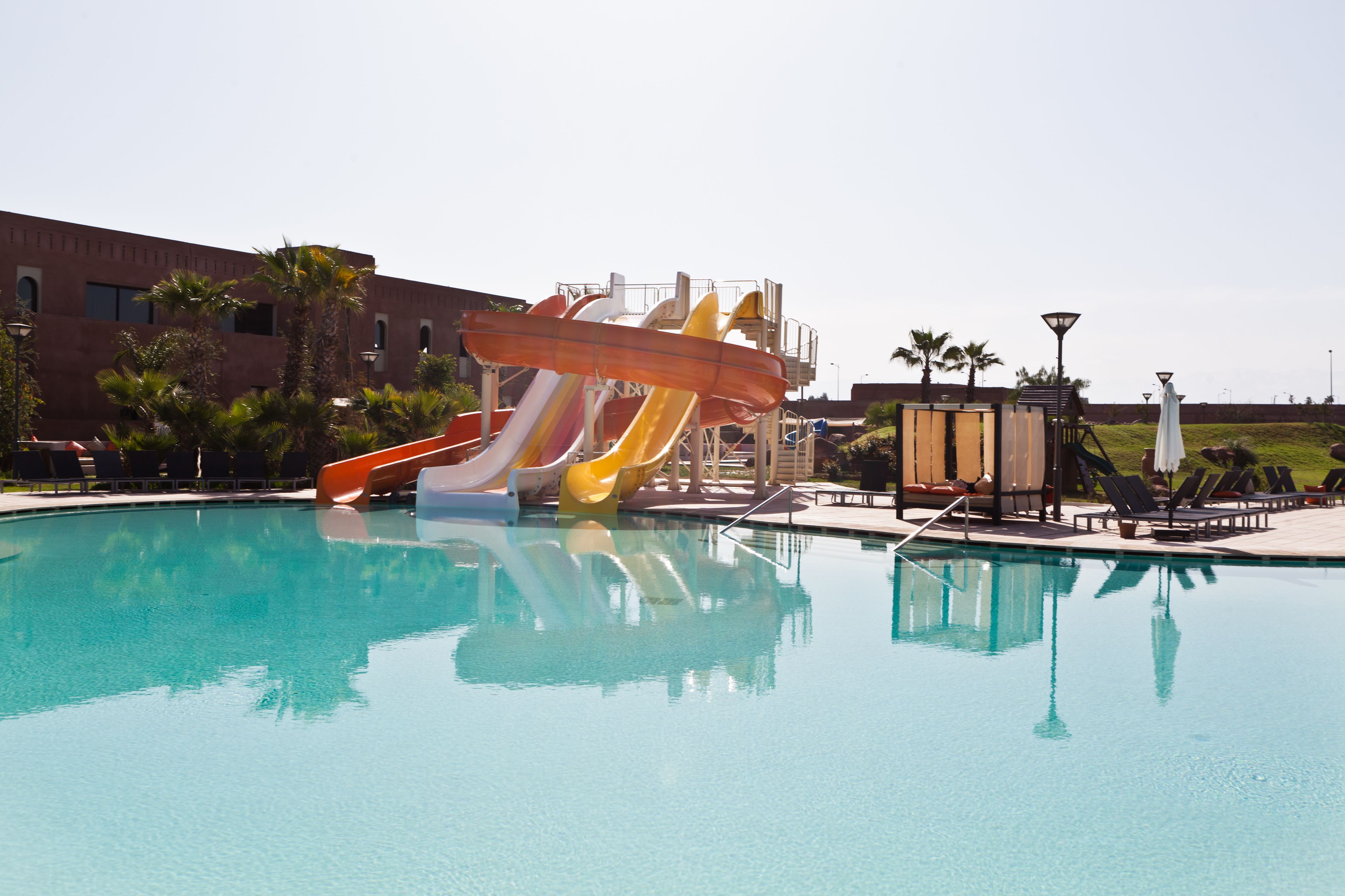 Piscina com vários toboáguas, um edifício ao fundo e céu claro.