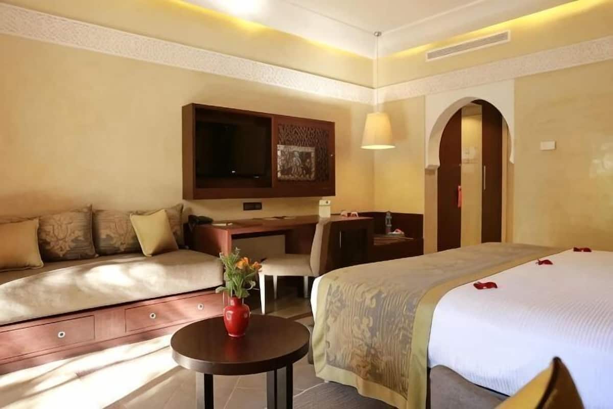 Una habitación de hotel con cama, sofá, escritorio y televisor.