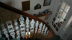 Eine Treppe mit aufwendiger weißer Geländer und einem hölzernen Handlauf.