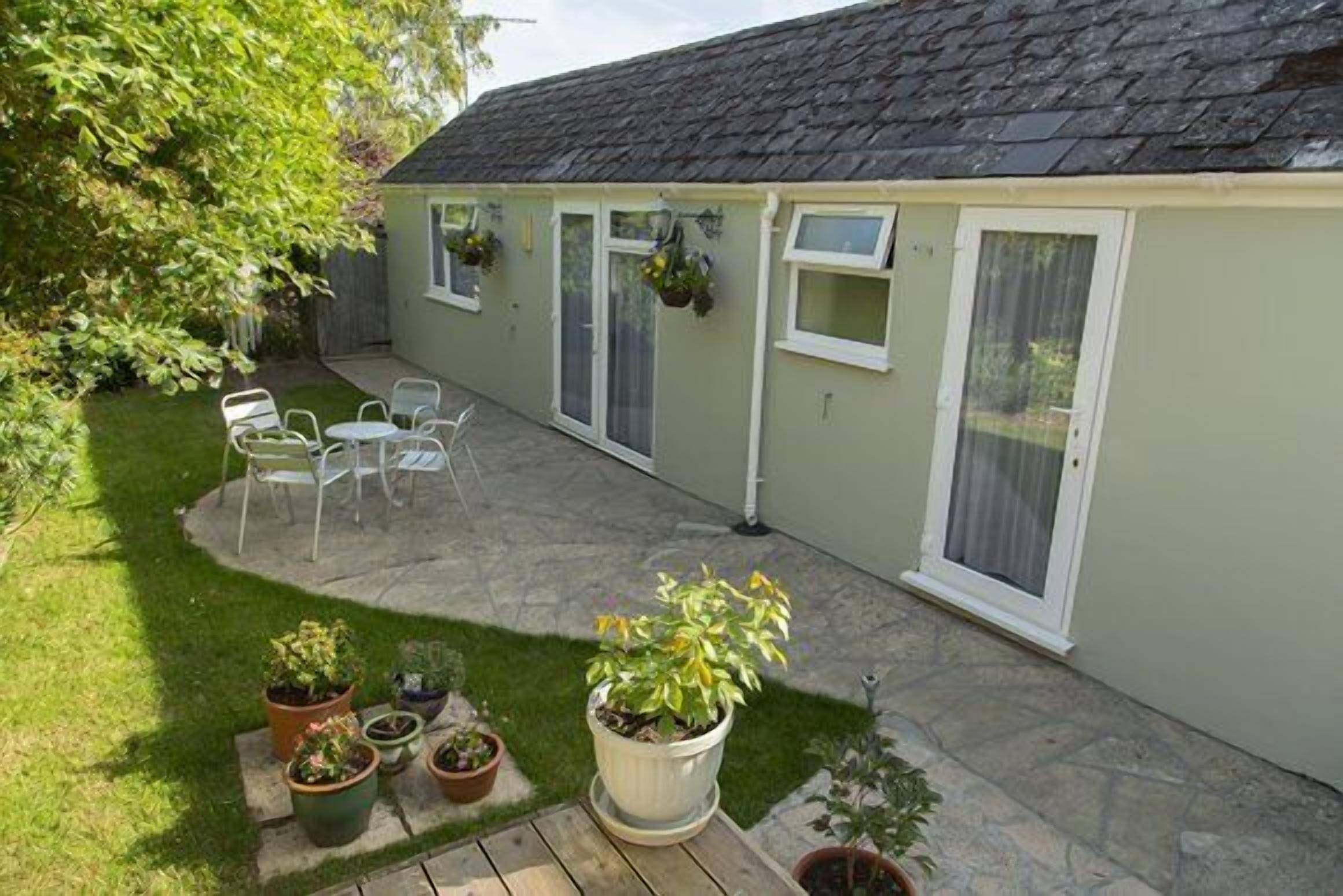 A patio area with a table and chairs, surrounded by potted plants and a small garden.