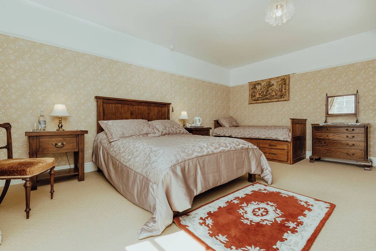 Een slaapkamer met twee bedden, houten meubels, een vloerkleed en een schilderij aan de muur.
