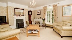 A living room with a fireplace, a sofa, a coffee table, and a television. - Smeaton Farm (Saltash)