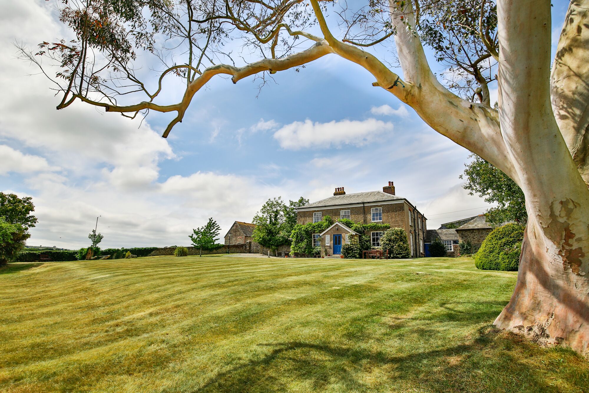 A large, historic house with a well-maintained lawn and mature trees.