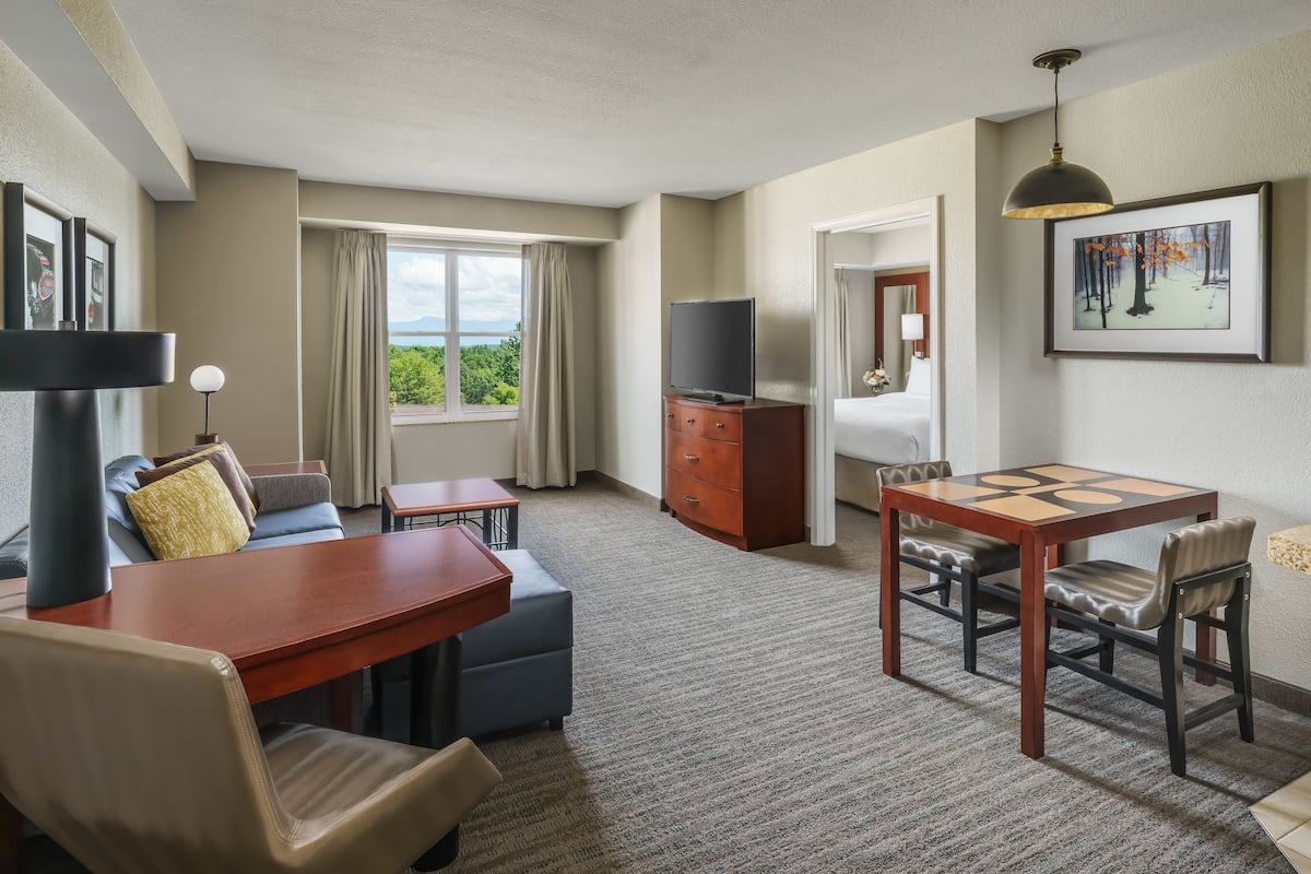 A hotel room with a sofa, a small table, a TV, a wooden cabinet, and a painting on the wall.