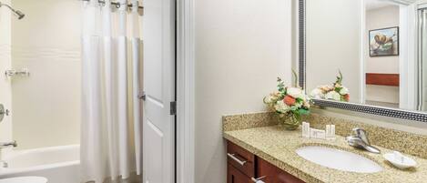 A bathroom with a shower, toilet, sink, and vanity.