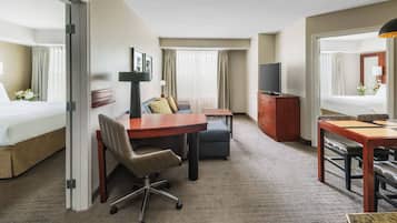 Une chambre d’hôtel comprenant un lit, un bureau avec une chaise, une télévision, une commode et un miroir.