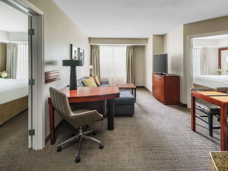 Une chambre d’hôtel comprenant un lit, un bureau avec une chaise, une télévision, une commode et un miroir.