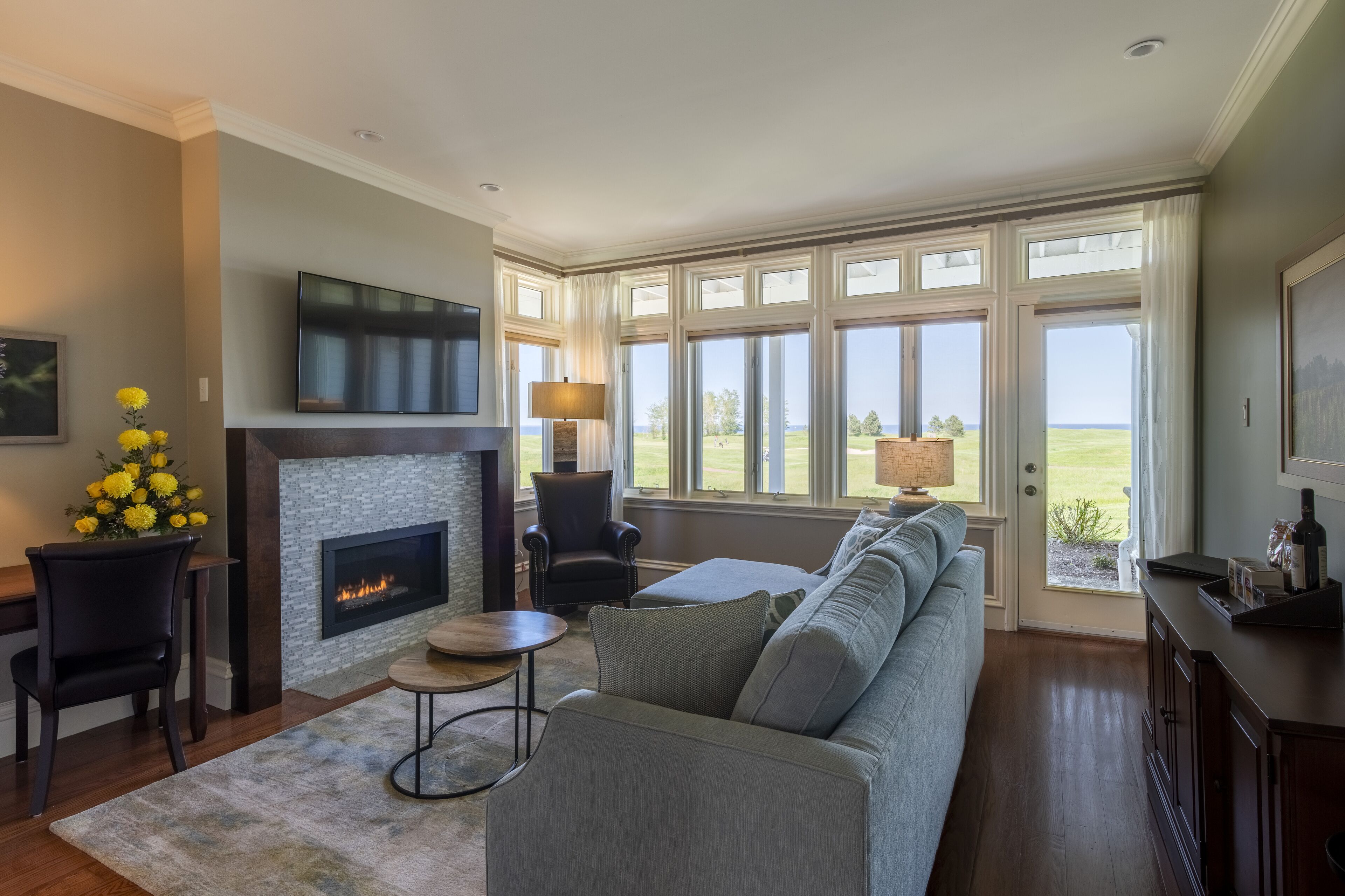 A living room with a fireplace, a sofa, a TV, and a view of the outdoors.