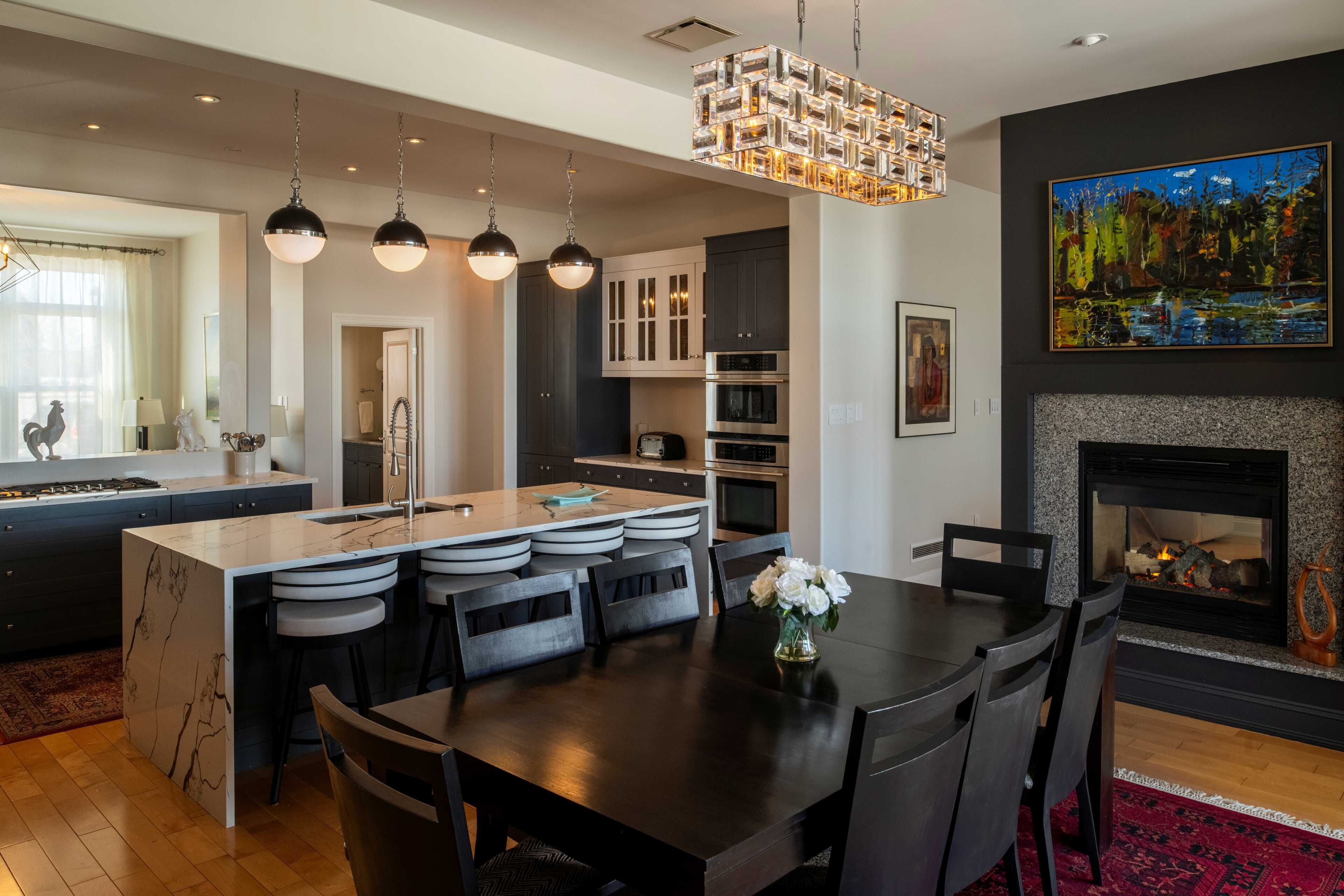 A modern kitchen with a central island, pendant lights, and a fireplace.