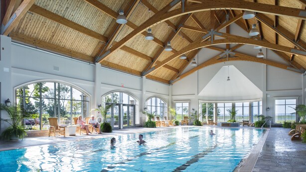 Una piscina interior con vigas de madera y ventanas amplias.
