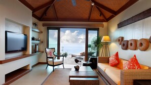 A spacious living room with a large TV, comfortable seating, a ceiling fan, and a view of the ocean. - Crimson Resort and Spa Mactan (Lapu-Lapu)